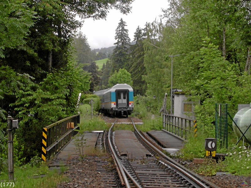 Bahn 177.jpg - Der Zug hat nach der Ausfahrt die kleine Brücke und den Übergang passiert. Die Schranken öffnen sich schon.